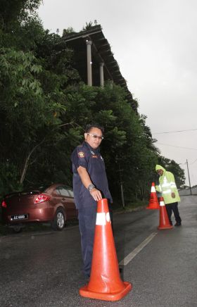 Safety first: Enforcement officers cordoning off part of Jalan 5/64 to ensure road users do not drive too close to the slope when it rains. - The Star
